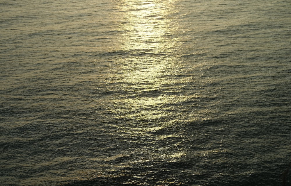 a body of water with a sun shining on it
