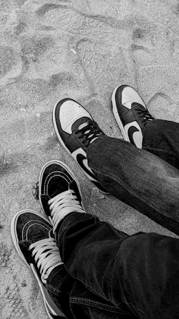 Minimalist black and white photo of two matching sneaker pairs side by side on a clean surface.
