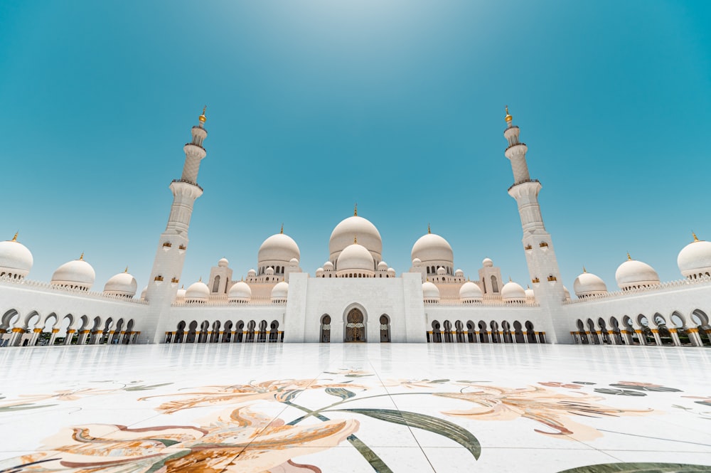 ein großes weißes Gebäude mit Türmen und der Sheikh Zayed Moschee im Hintergrund