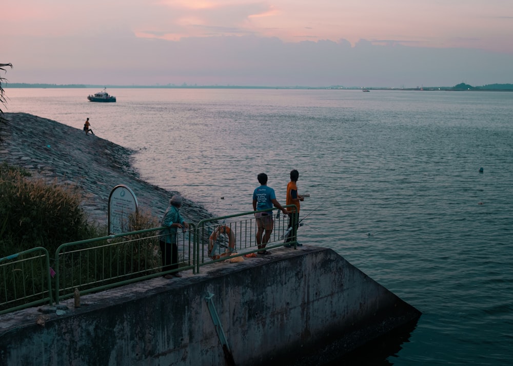 a group of people standing on a railing overlooking a body of water