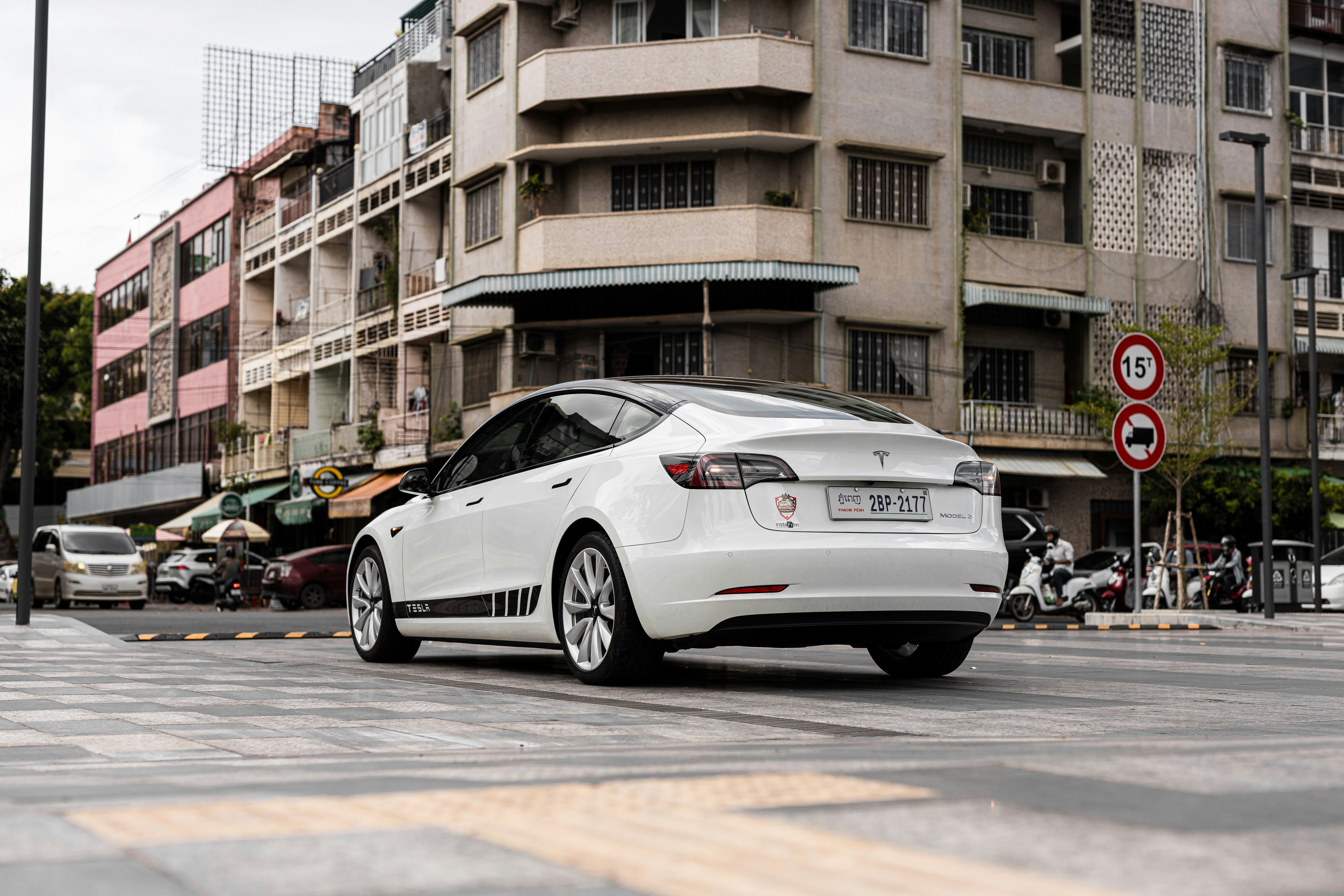 White Tesla Model S electric sedan on clean urban road with modern city backdrop