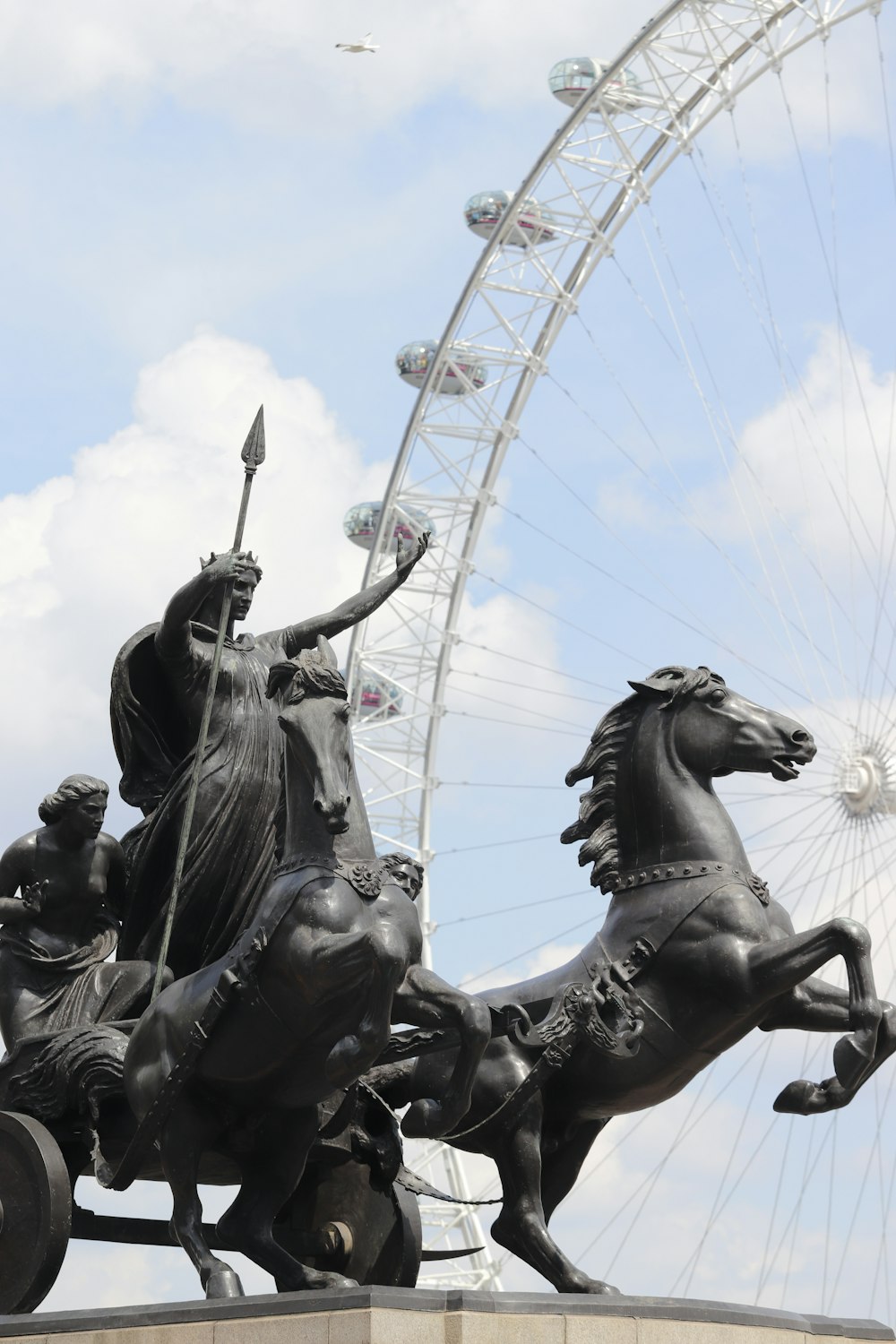 a statue of a person riding a horse next to a ferris wheel with Marine Corps War Memorial in the background