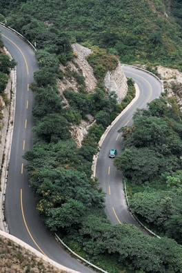 A winding mountain road near Nizwa with lush greenery and a comfortable car cruising along.