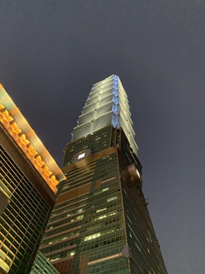 Evening shot of a high-rise building glowing with navy blue lighting and golden accents