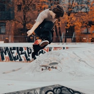 An action shot of a skateboarder mid-jump against a colorful urban backdrop.
