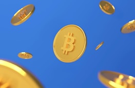 Several golden coins featuring the Bitcoin symbol appear to be floating in front of a solid blue background. The coins vary in size, and their shiny surfaces reflect light, creating a dynamic visual effect.