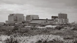 Wide shot of an industrial factory building clad with metal sheets in desert surroundings.