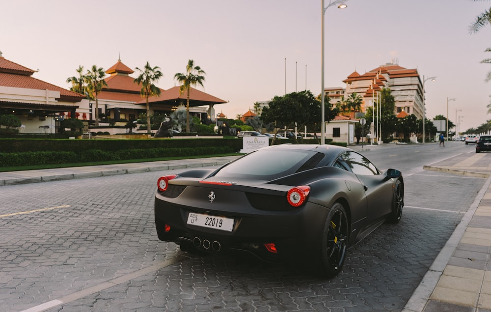 a black sports car parked on a street with palm trees and buildings