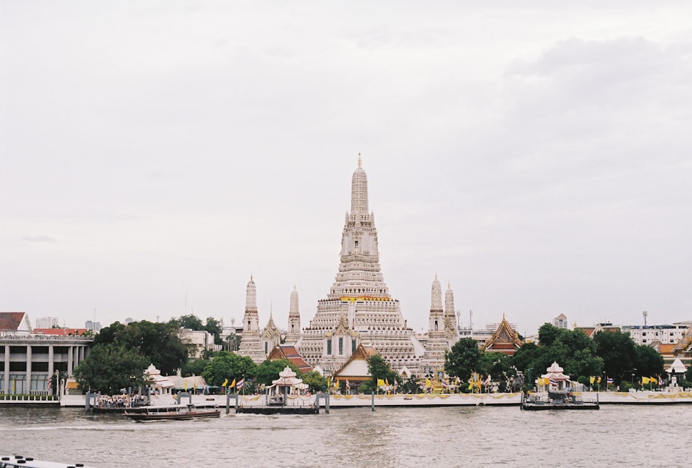 배경에 Wat Arun이있는 수역 옆에 뾰족한 탑이있는 큰 건물