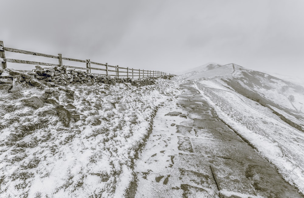 a snowy road with a fence and a wooden fence