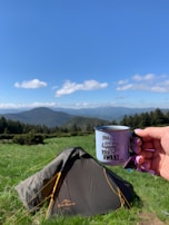 Close-up of a hand holding a ceramic mug embossed with an encouraging scripture verse.