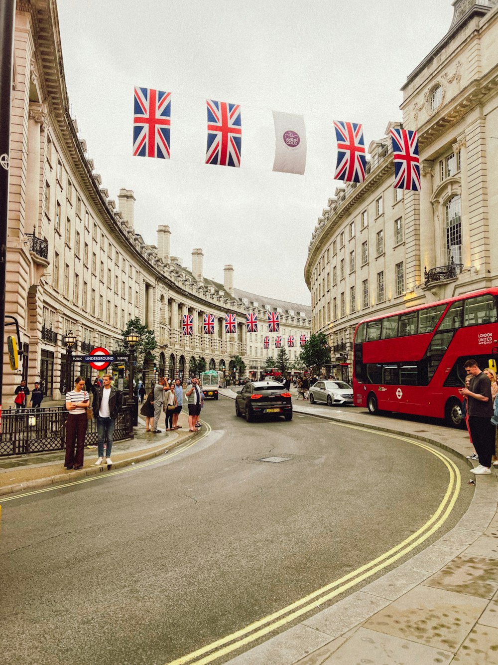 a street with cars and people on it with flags on the side