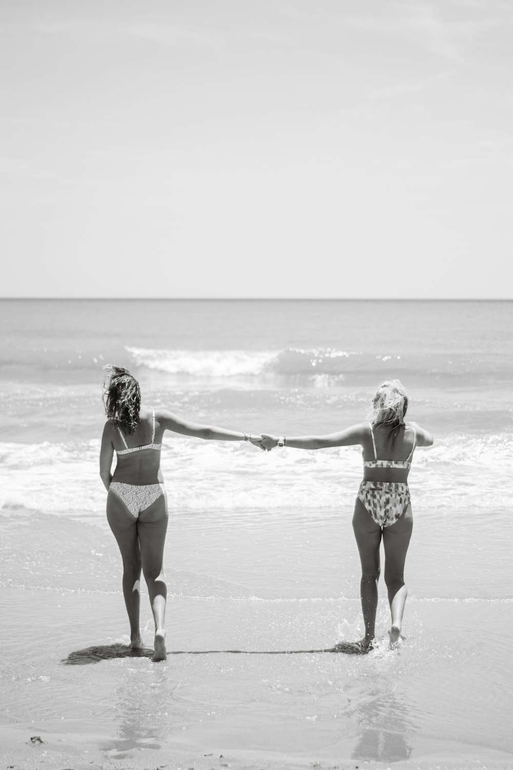two women holding hands on a beach