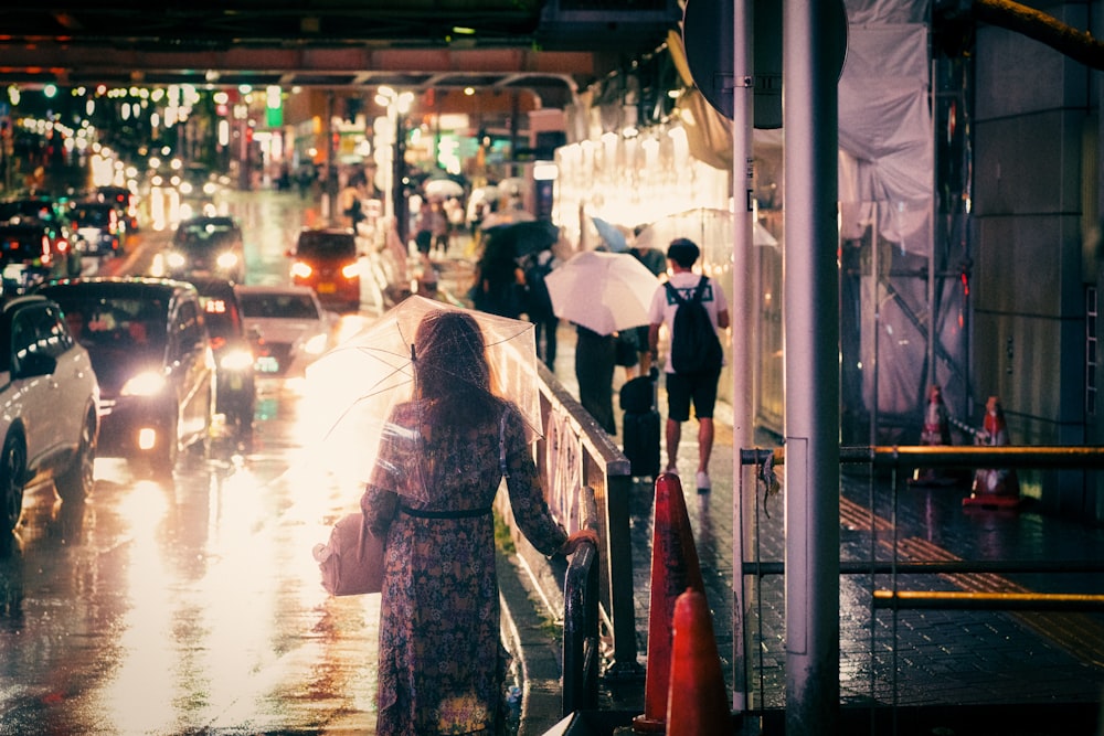 a man walking down a sidewalk with an umbrella