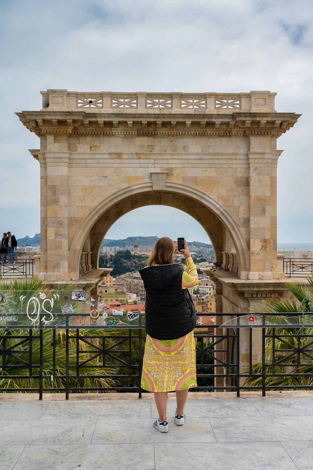 a person taking a picture of a large stone arch