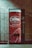 A vending machine with a bright red design featuring white text and decorative bubbles. It has the branding 'Drink Cheerwine Bottling Company' prominently displayed. The machine is set against a tiled wall in a dimly lit area.