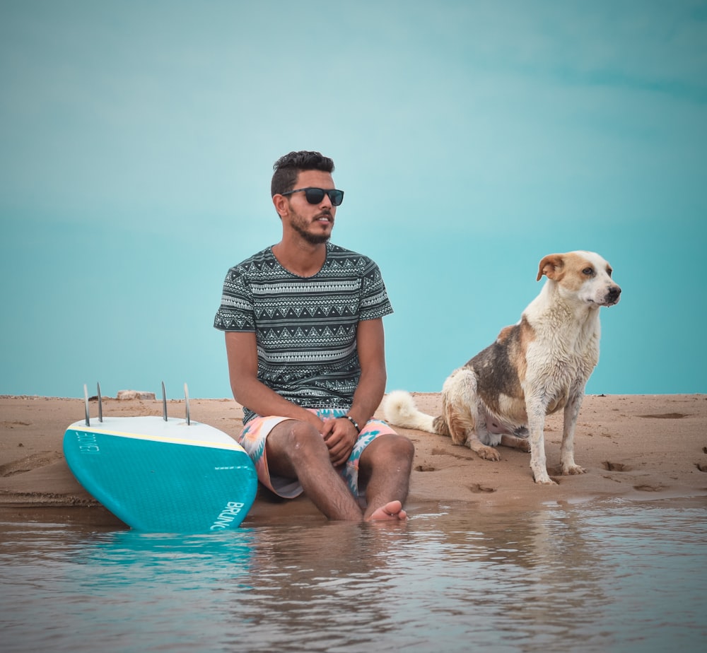 a man and a dog sitting on a beach