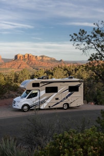 an rv parked on a road with trees and mountains in the background