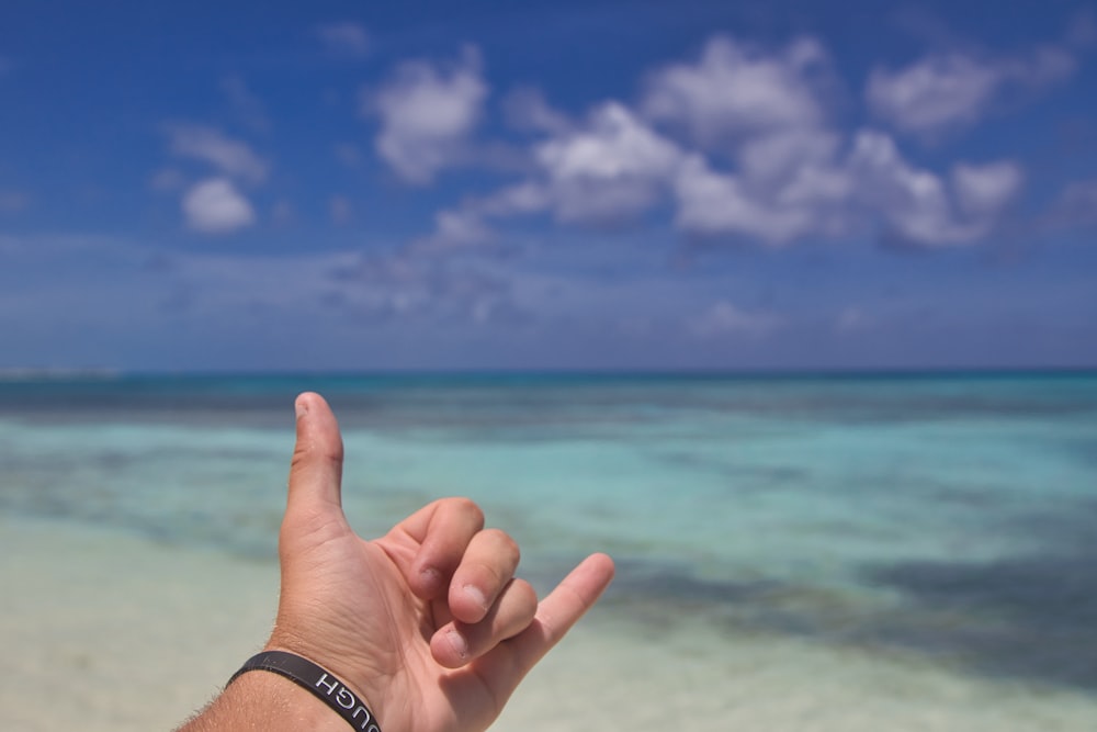 a hand with a thumb up on a beach