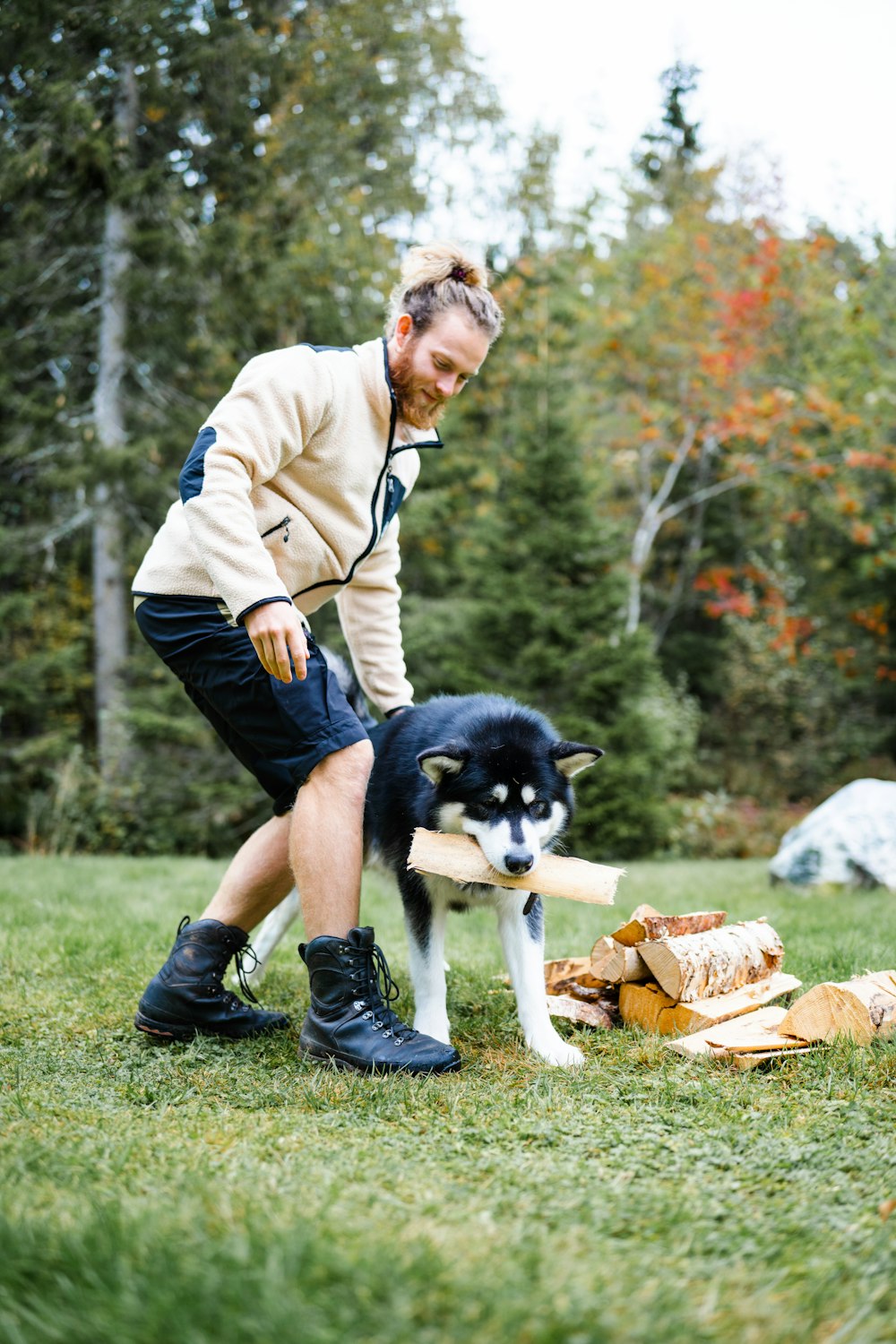 a man kneeling down next to a dog in a park