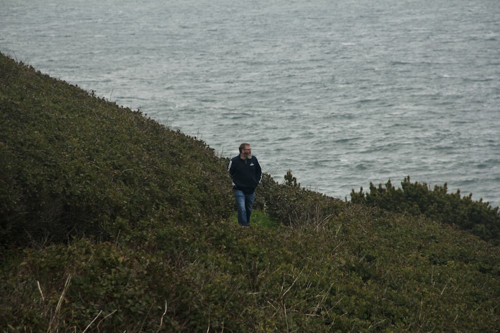 a man standing on a hill by the water