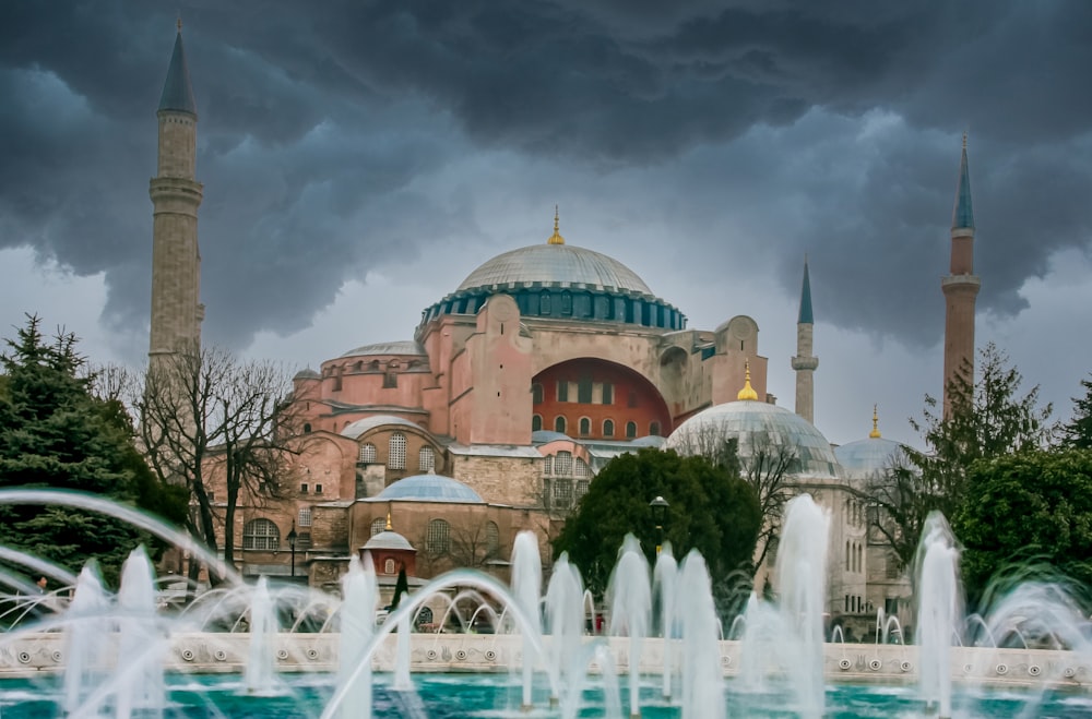 ein großes Gebäude mit Türmen und einem Brunnen davor mit der Hagia Sophia im Hintergrund