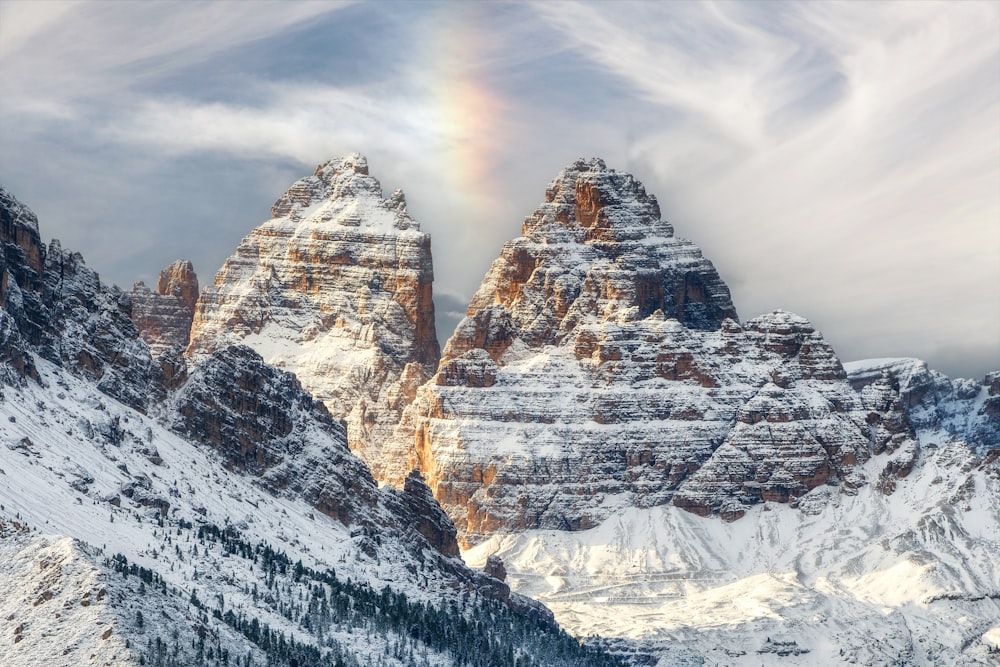 a snowy mountain with a rainbow