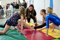 Coaches demonstrating gymnastics techniques to attentive children.