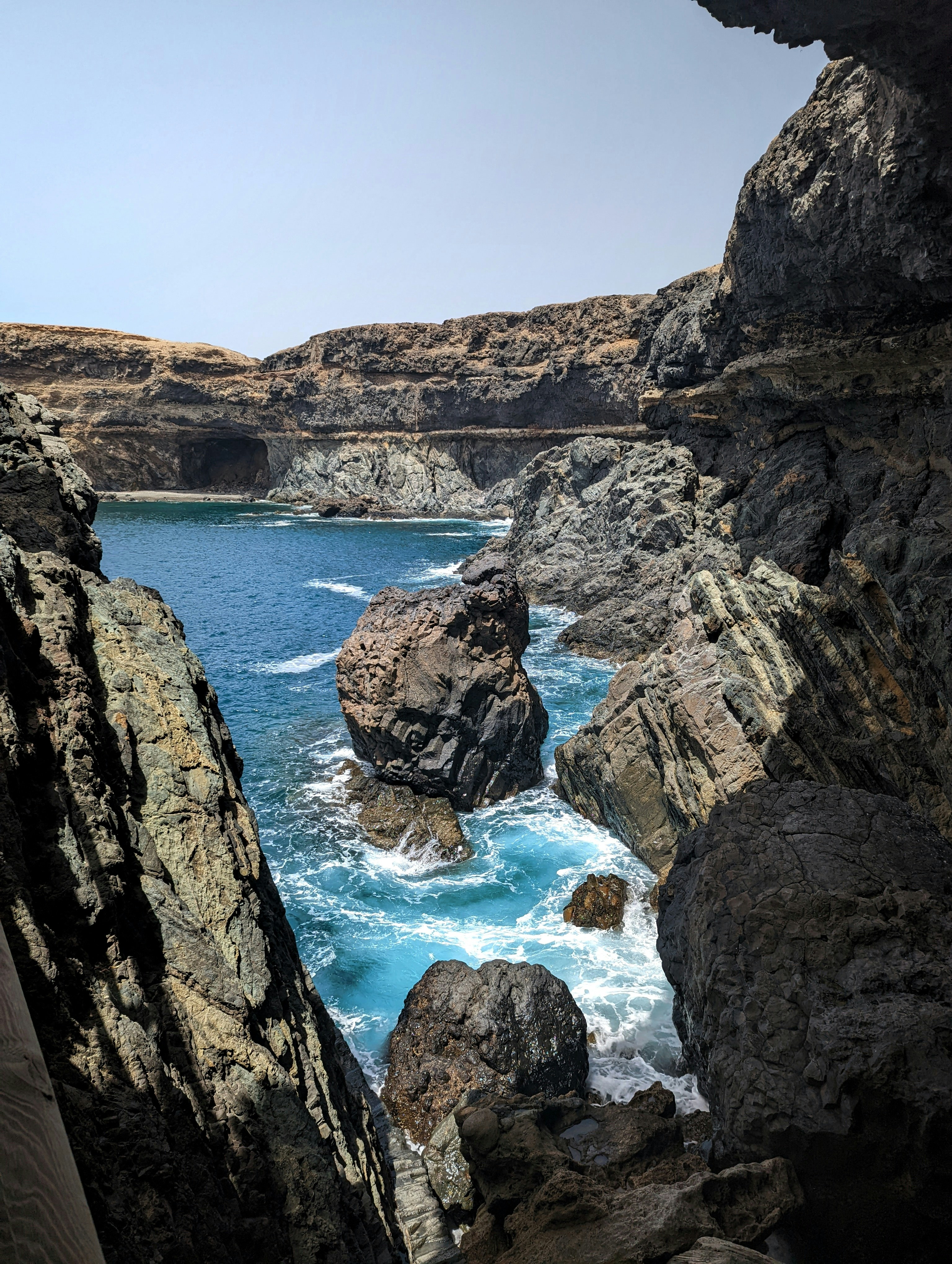 a rocky cliff with a body of water below