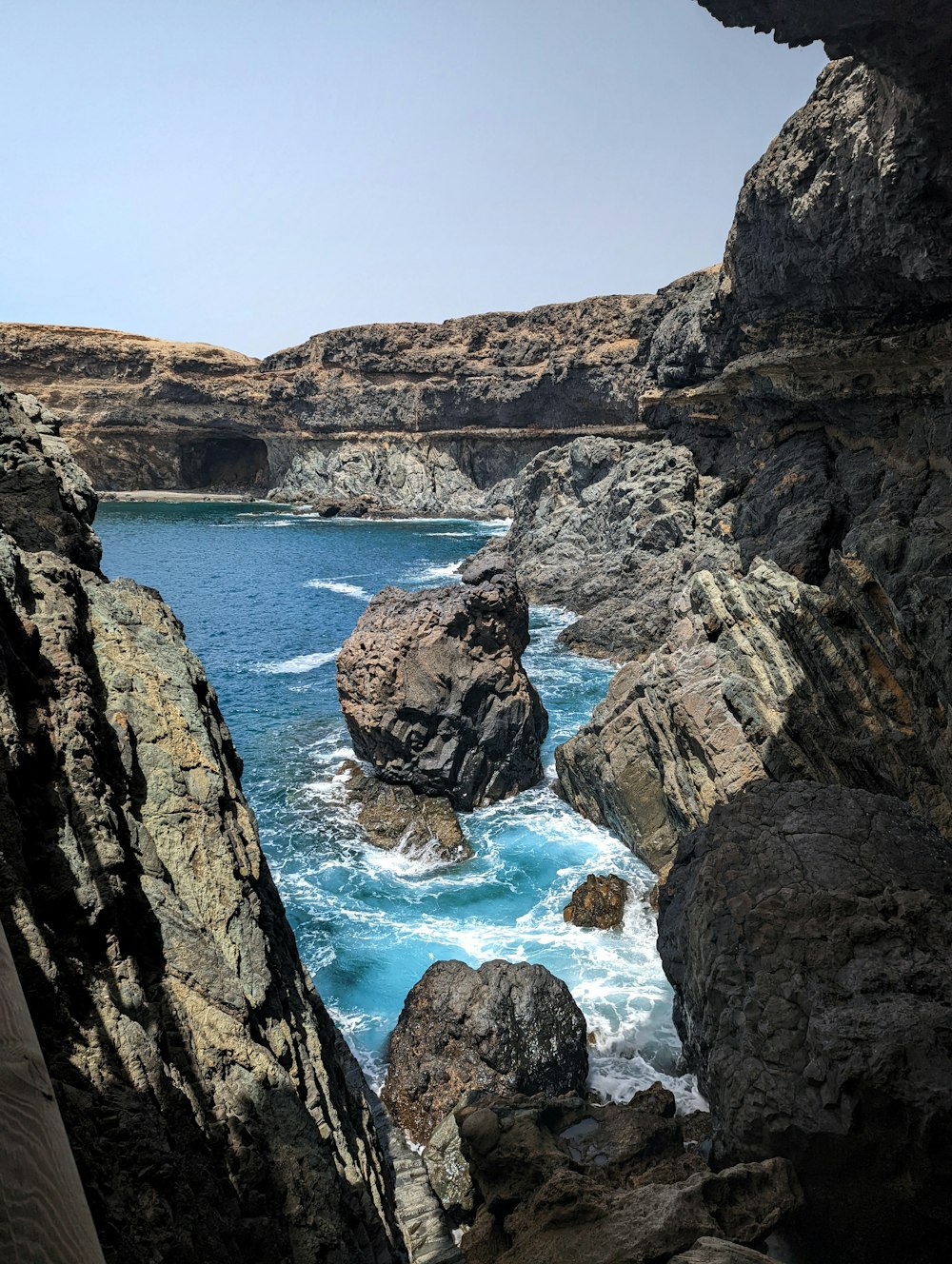 a rocky cliff with a body of water below