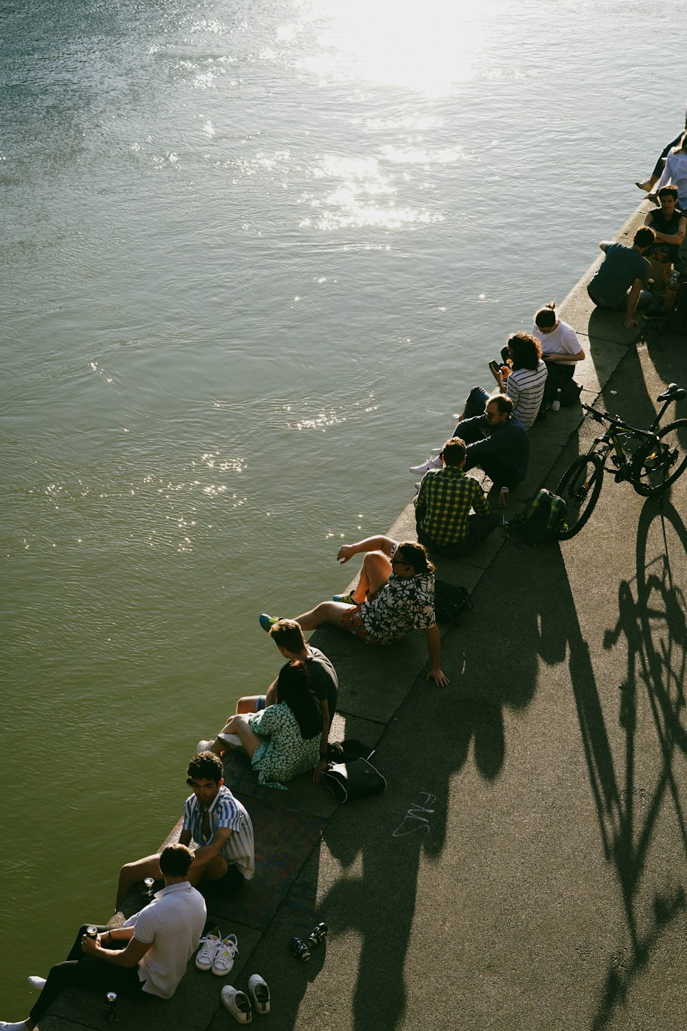 a group of people sitting on a bench by a body of water