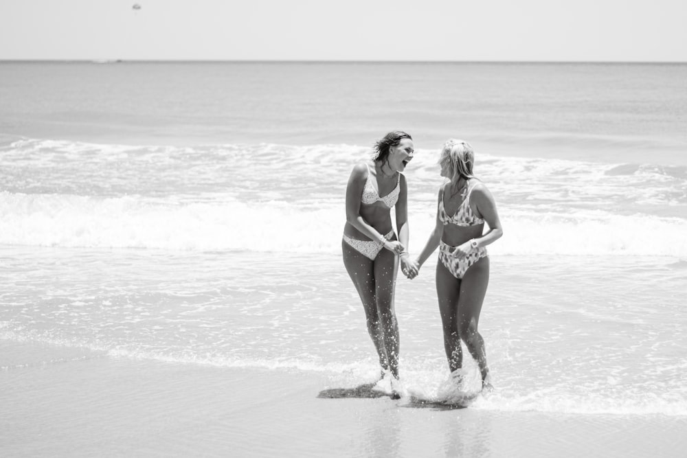two women in swimsuits walking on the beach