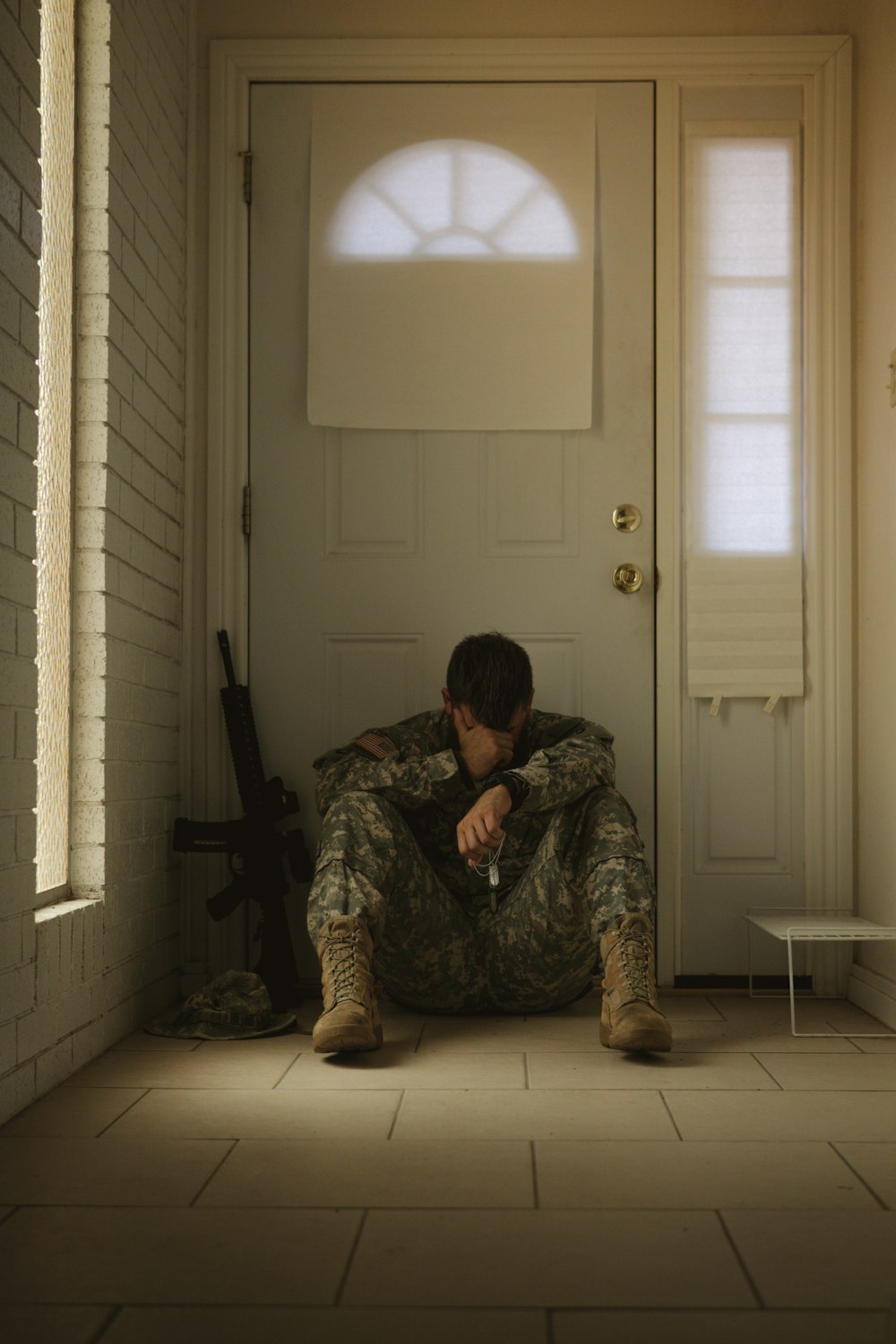 a person in camouflage kneeling in front of a door