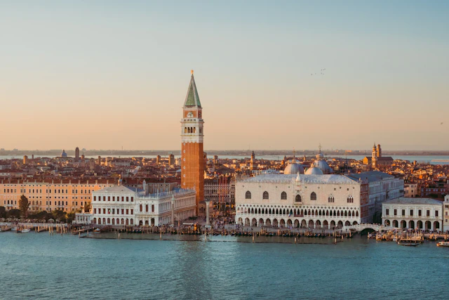 An elevated view over St Mark's Campanile and the Doge's Palace at sunset from the water.