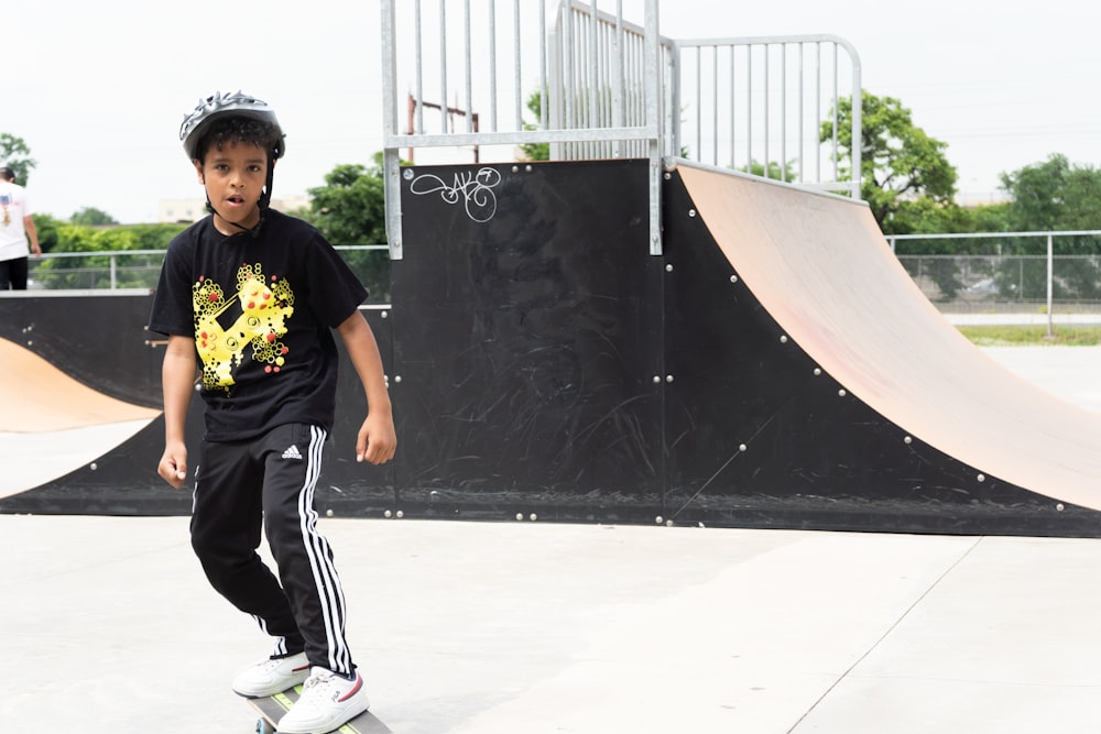 a boy wearing a helmet and standing in front of a skate park
