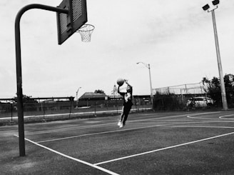 A sleek black and white photograph of a dynamic basketball player mid-air, framed elegantly against a dark background.