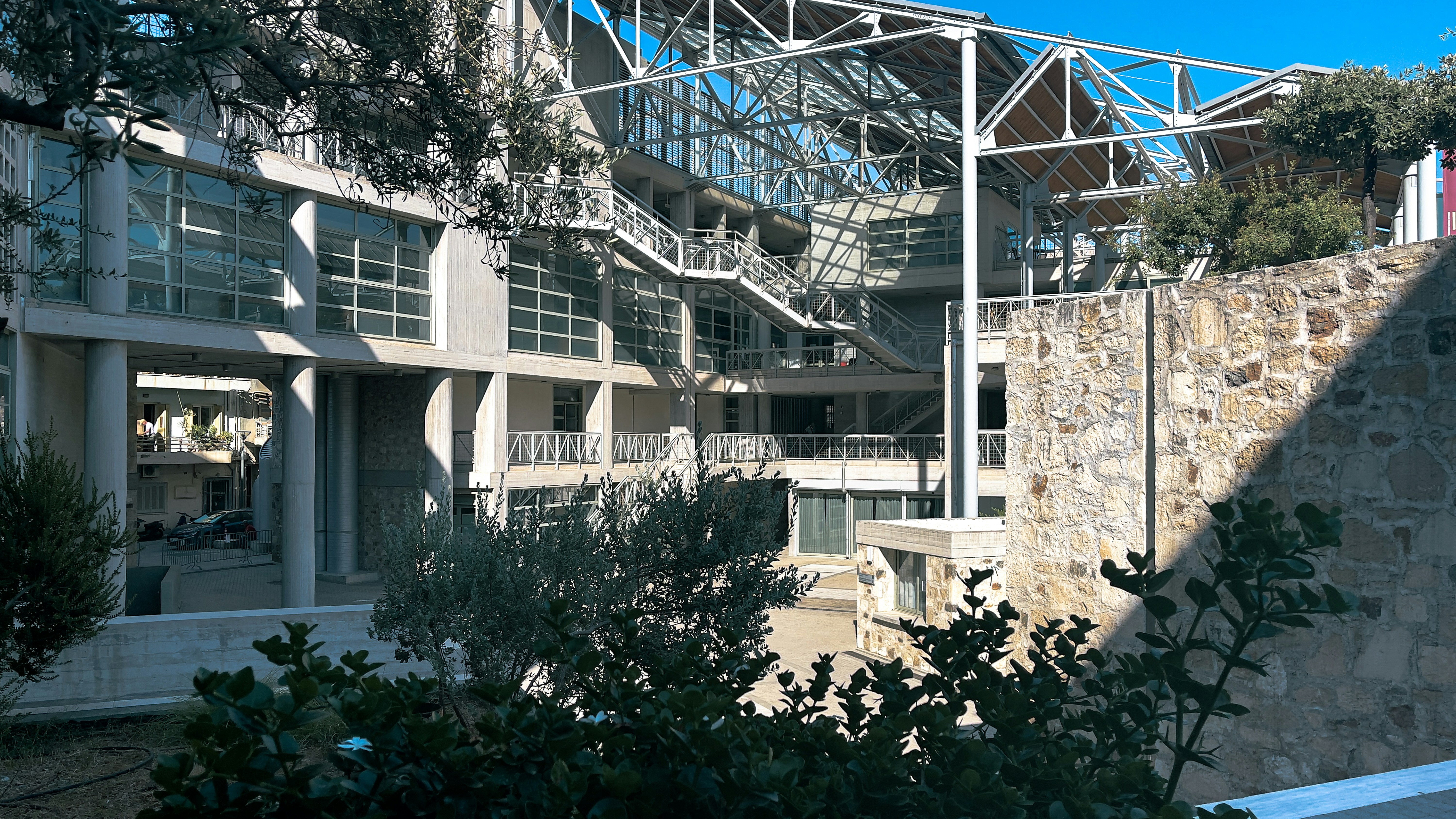a building with a stone wall and trees in front of it