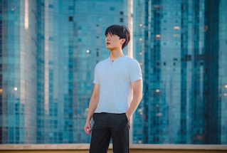 An ambitious Indian student with a backpack and laptop, standing confidently with global university landmarks subtly blended in the background.