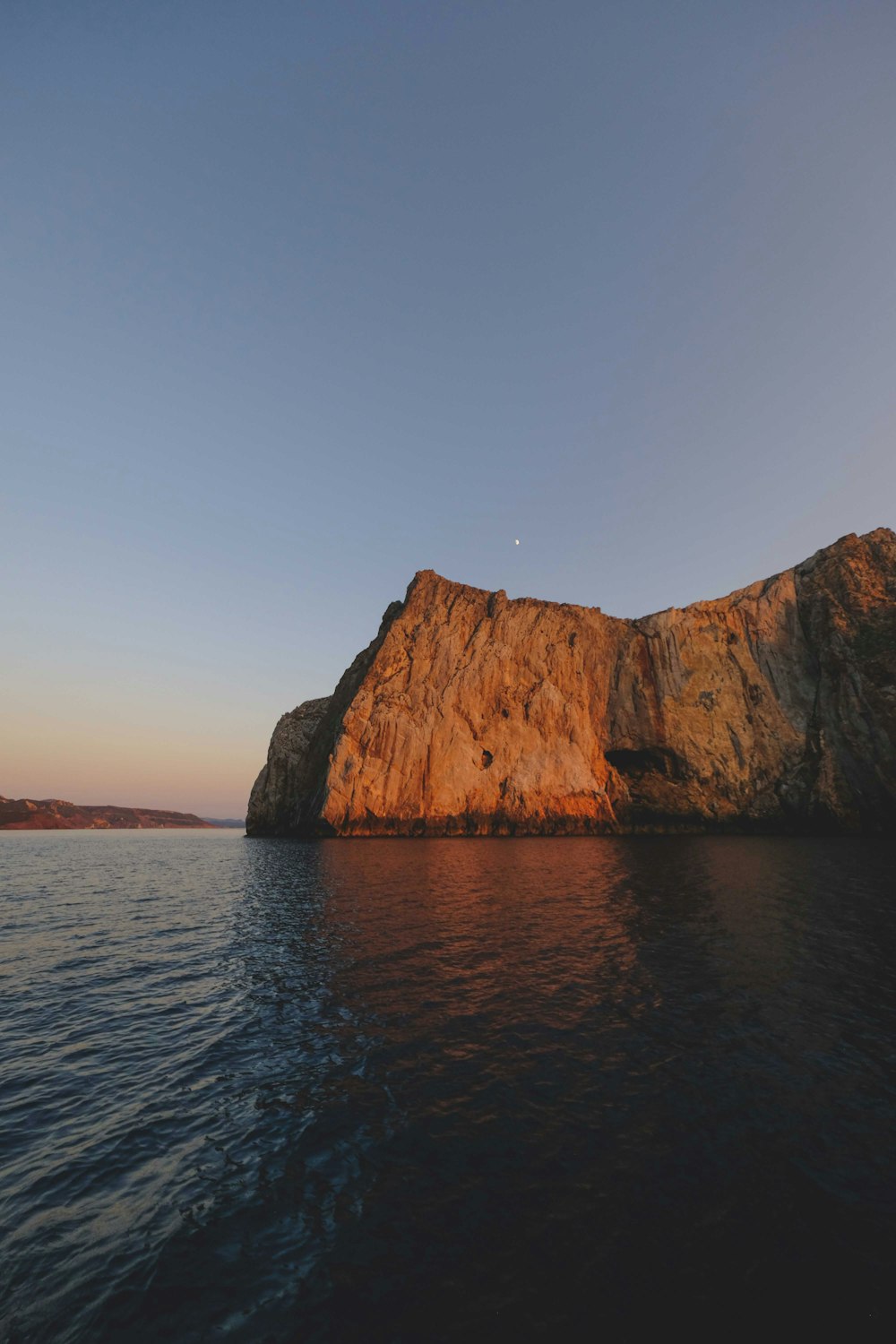 a body of water with a rocky cliff in the background