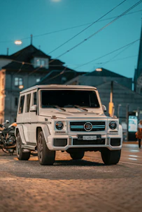 A sleek white SUV parked in front of a bustling Casablanca street at sunset.