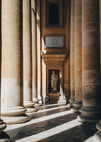 a room with columns and a statue in the center