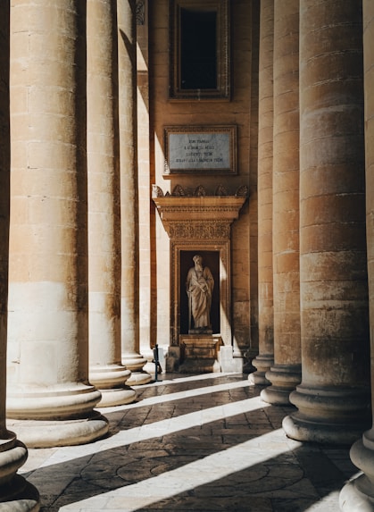 a room with columns and a statue in the center