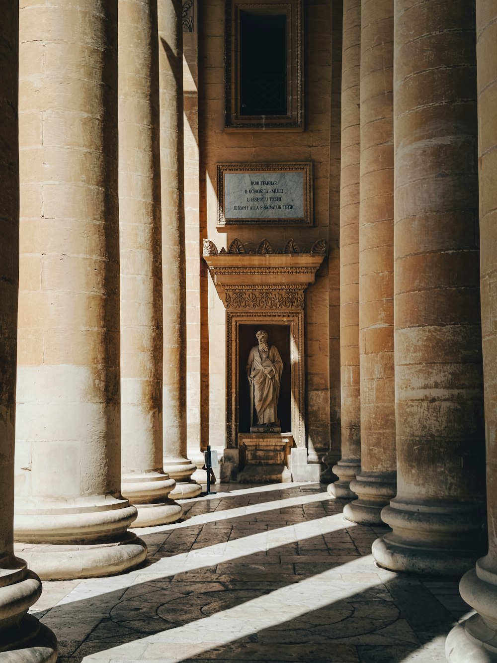 a room with columns and a statue in the center