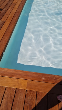 Close-up of a sleek swim fin resting on a textured pool deck with water reflections.