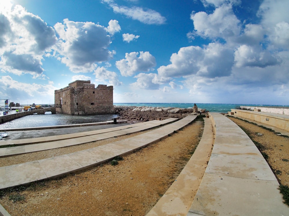 a stone wall with a walkway and a stone building on the side