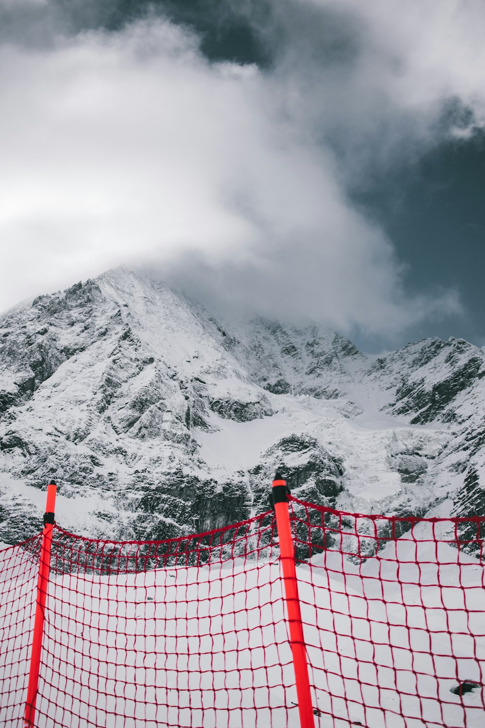 a red fence in front of a snowy mountain