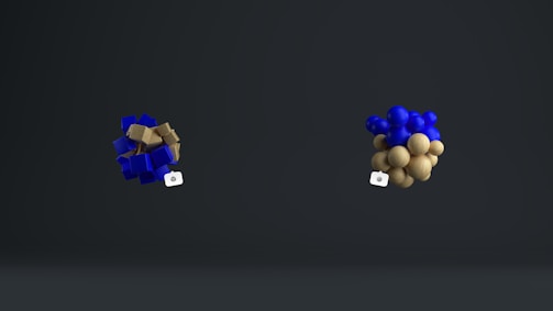 Two abstract clusters are positioned against a dark background. The left cluster consists of blue cubes interspersed with brown cubic elements, while the right cluster is made up of blue and brown spheres. Both clusters appear to hover in mid-air with small, camera-like icons attached.