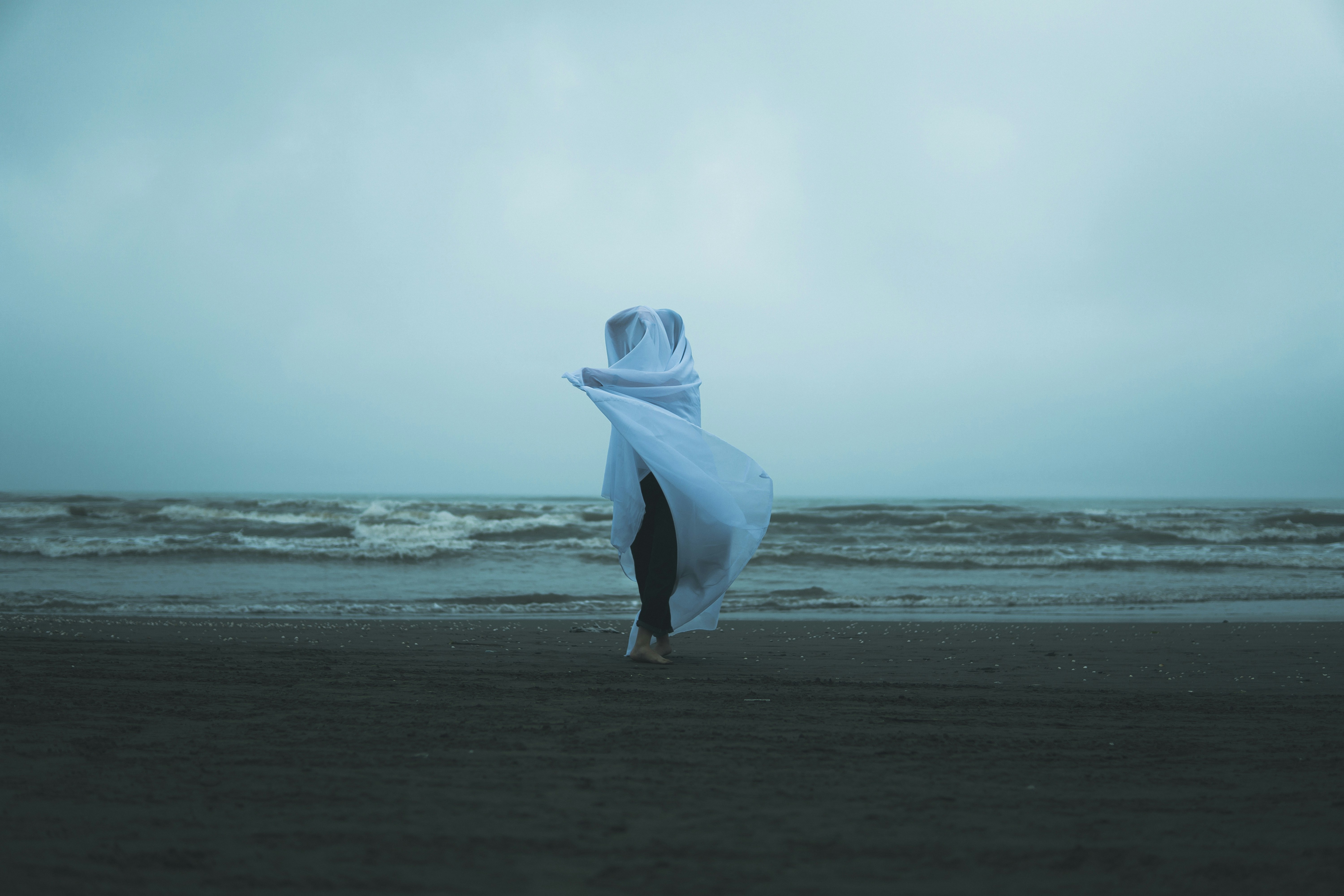 A person holding a white umbrella on a beach