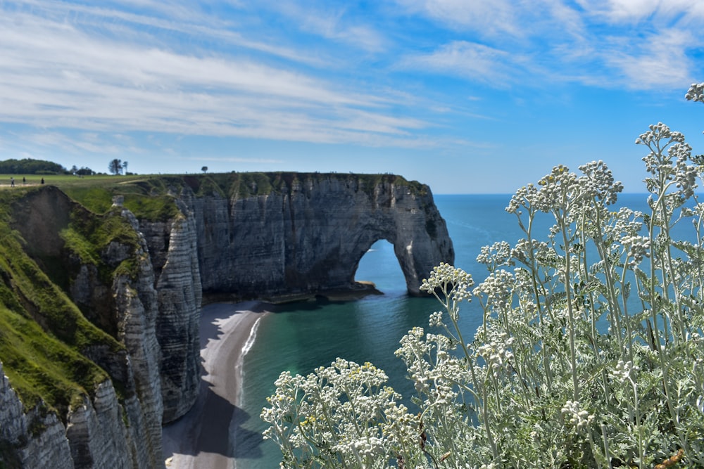 a cliff with a beach and blue water below