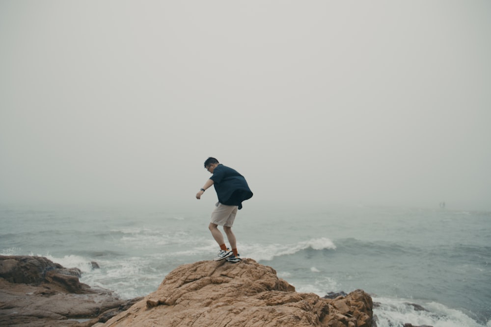a man standing on a rock by the ocean
